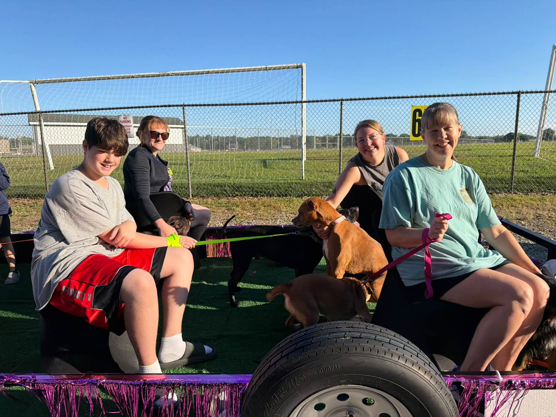 Families and adoptable dogs sitting together on the decorated parade trailer before the parade begins