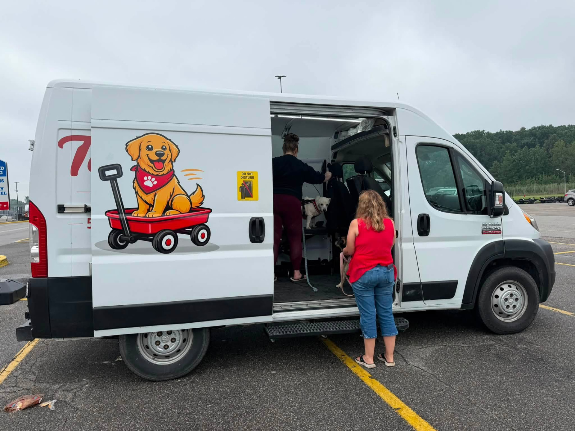The Tail Wagon mobile grooming van at Tractor Supply with the team grooming a small white dog inside