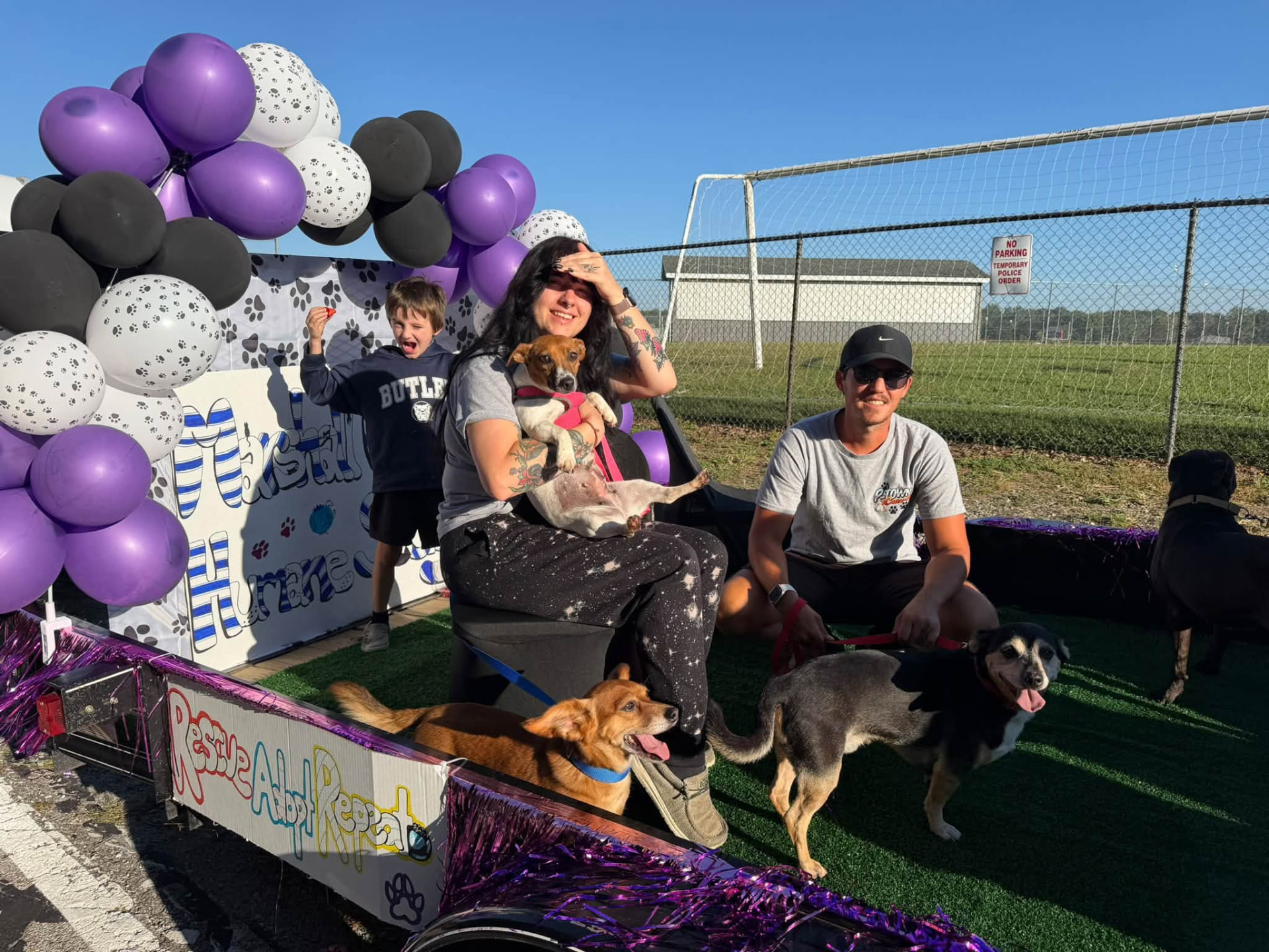 Volunteers and rescue dogs on the Marshall County Humane Society float, framed by purple, black and paw-print balloons